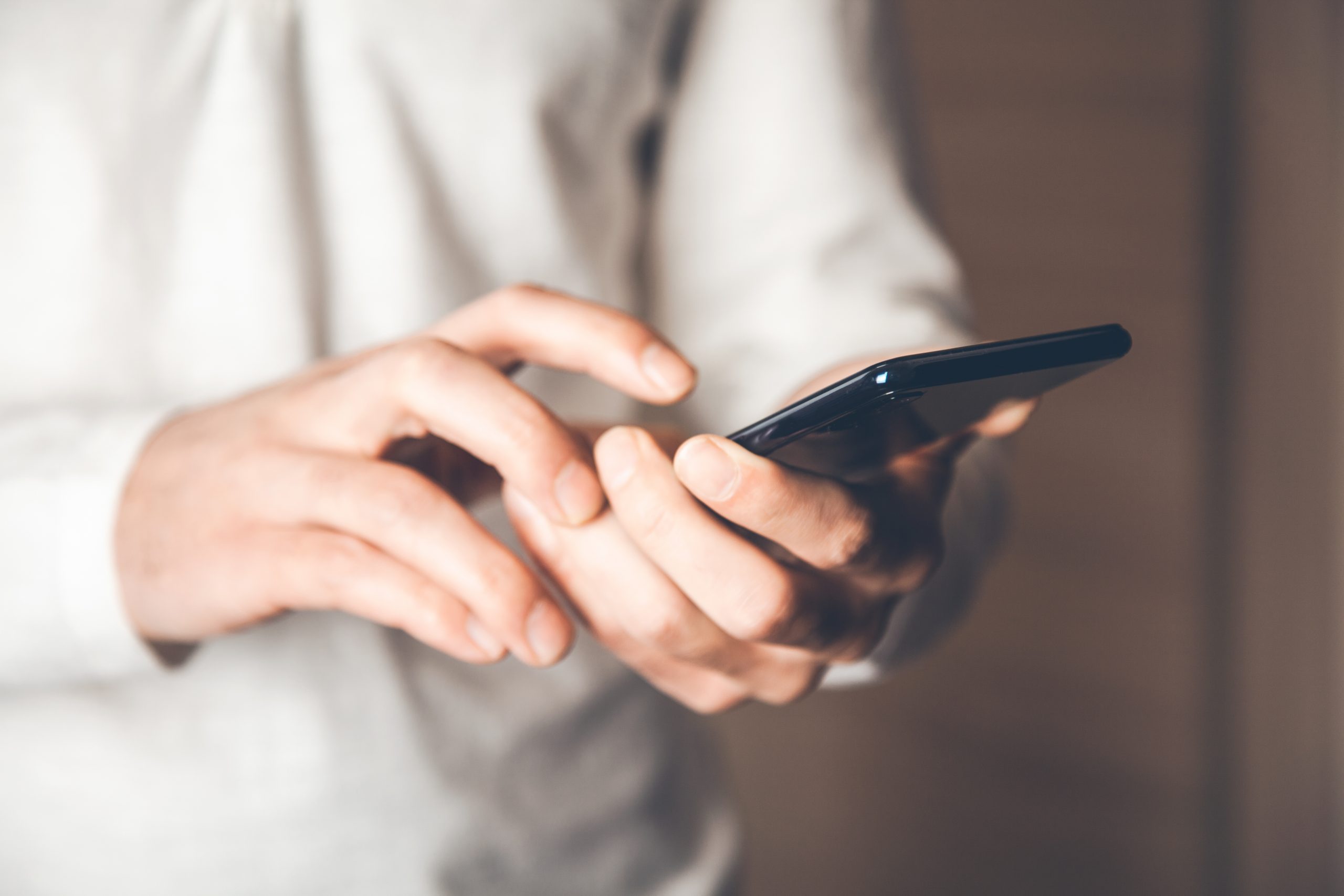 Hände die ein Handy bedienen, vielleicht für die Kontaktaufnahme mit Just Ci