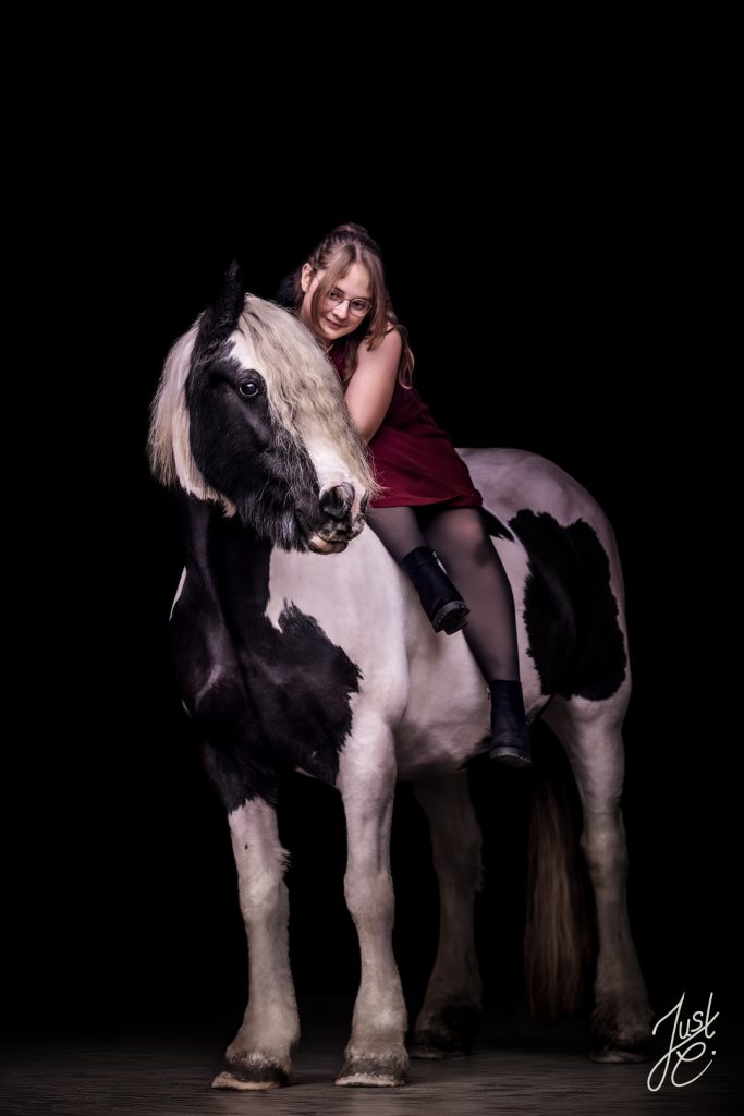 liebevolles Pferdebild einem Tinker und seine Besitzerin vor schwarzen Hintergrund beim mobilen Pferdeshooting in Diepholz