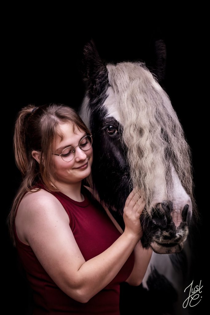 Emotionales Pferdeportrait von einer Tinker Stute und ihre Besitzerin bei einem Shooting schwarzen Hintergrund Fotos